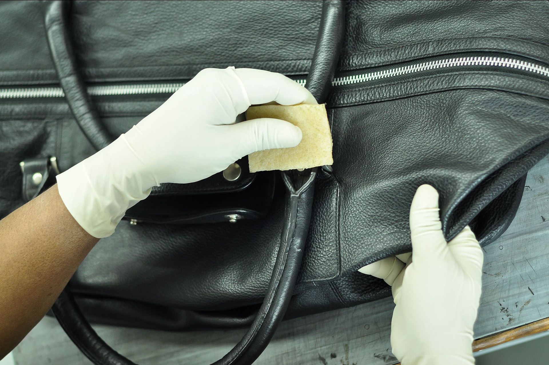 A specialist working on a leather duffle bag representing the luggage repair services of Klumpps Leather & Luggage in Grand Rapids, MI